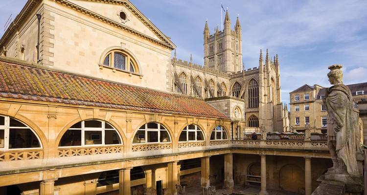 Élégante cour des thermes romains avec l'abbaye de Bath qui s'élève derrière sous un ciel bleu
