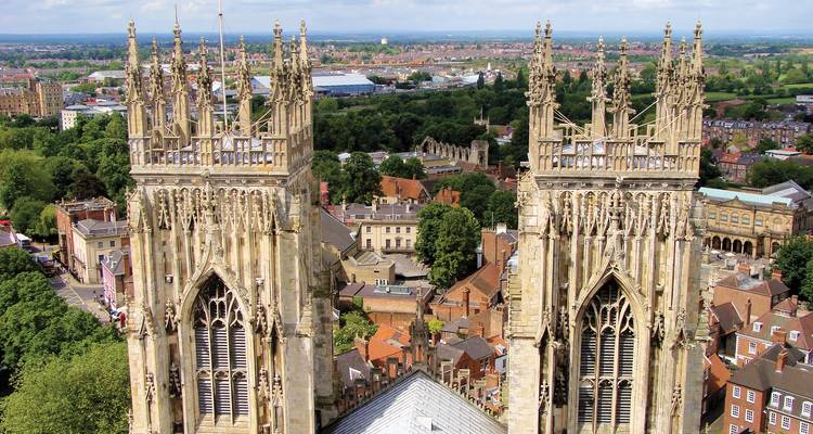 Les tours jumelles ouest de la cathédrale d'York s'élèvent au-dessus du paysage urbain médiéval sous un ciel lumineux.