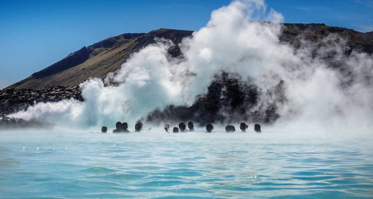 Les baigneurs qui se prélassent profitent des eaux géothermales bleu laiteux au milieu de la vapeur montante au Lagon Bleu d'Islande.