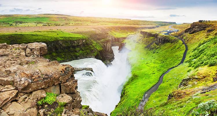 La puissante chute d'eau de Gullfoss plonge dans un canyon verdoyant sous la douce lumière du soir.