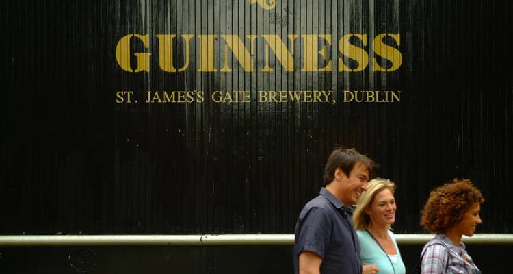 Amigos pasean frente a la icónica puerta de Guinness en la Cervecería St. James's Gate