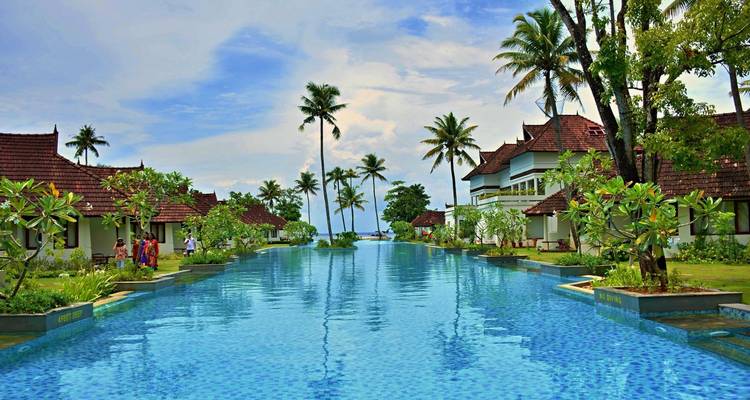 Luxuriöses Resort mit einem langen Infinity-Pool, gesäumt von Palmen und traditioneller Kerala-Architektur.