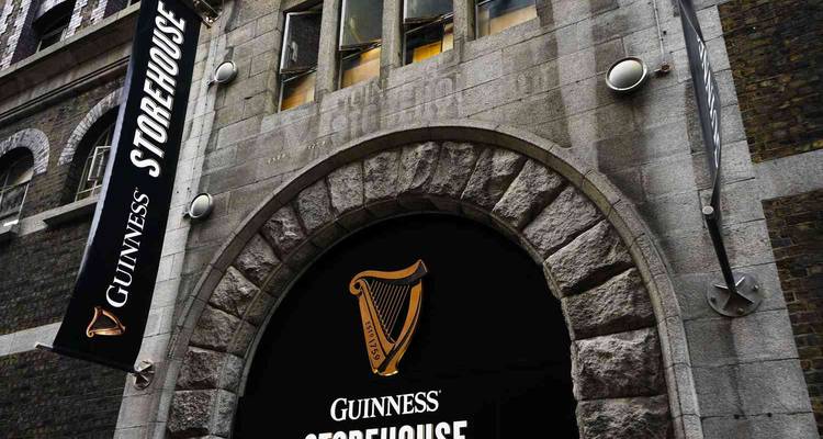 Fachada de arco de piedra y entrada negra que lleva el logo del arpa del Guinness Storehouse.