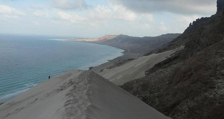 Vista panorámica desde la cima de una duna alta que desciende hacia una costa remota.