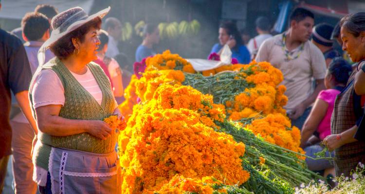 Vendeur local arrangeant de vives fleurs de souci orange sur un marché en plein air entouré d'acheteurs.
