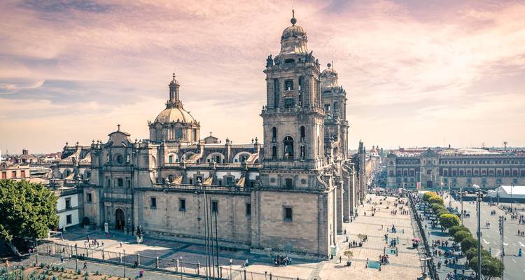 Vue latérale élégante de la Cathédrale métropolitaine de Mexico baignée de lumière chaude avec des visiteurs sur la place.