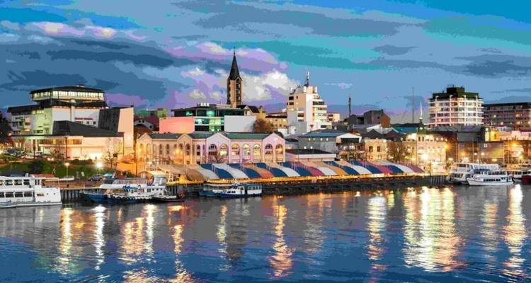 Paysage urbain coloré du front de mer au crépuscule reflété dans les eaux calmes avec des nuages dramatiques.