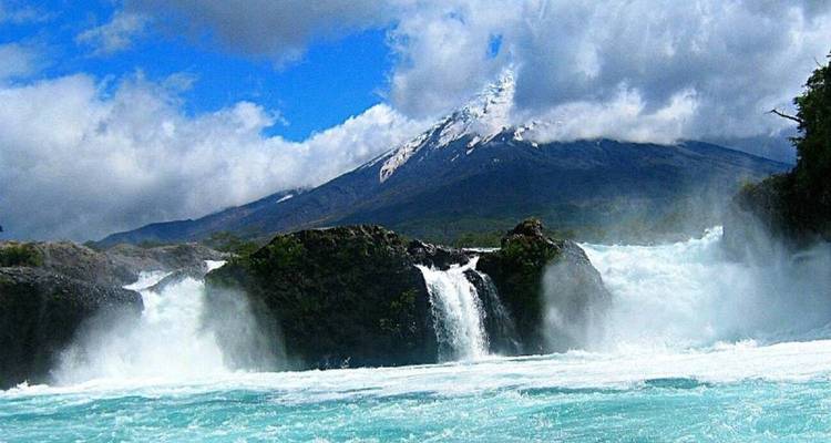 Les chutes de Petrohué grondantes encadrées par une eau émeraude et le volcan Osorno coiffé de neige au loin.