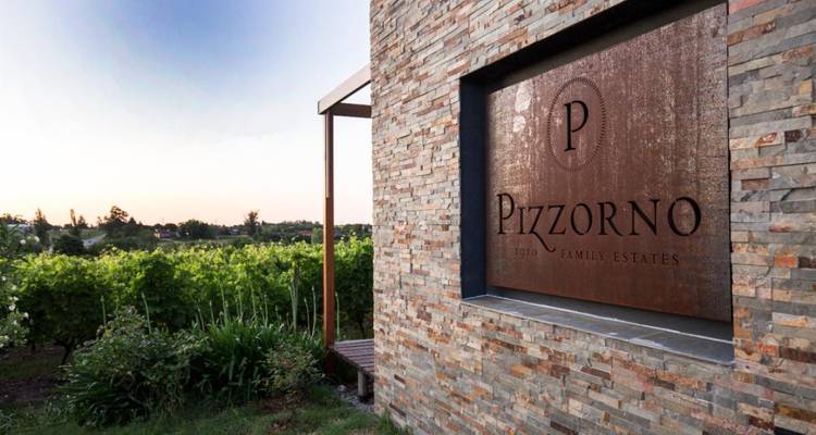 Stone and wood sign for Pizzorno Family Estates winery overlooking lush green vines.