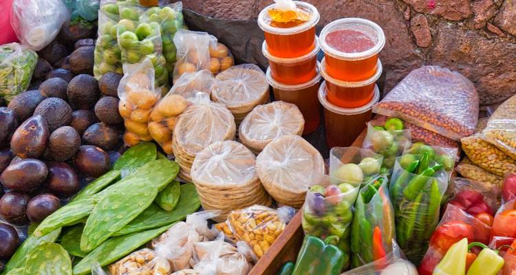 Assortiment coloré de produits frais, pots de miel et collations locales à un étal de marché mexicain