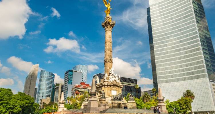 Monument de l'Ange de l'Indépendance s'élevant devant des gratte-ciel modernes sous un ciel bleu éclatant