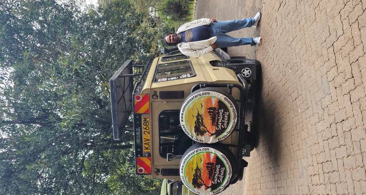 Homme debout à côté d'un véhicule de safari marqué de grands logos circulaires de safari.