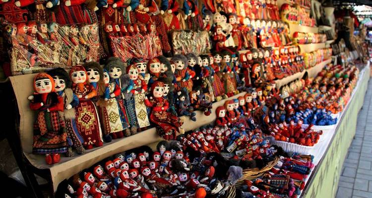 Puesto de mercado colorido alineado con filas de muñecas y artesanías tradicionales armenias.