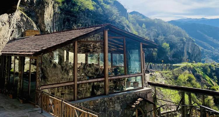 Cafetería de madera y vidrio ubicada en una carretera montañosa boscosa.