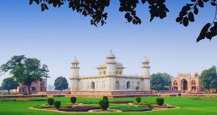 Het ivooorwitte Itimad-Ud-Daulah mausoleum staat in weelderige tuinen omlijst door blauwe lucht in Agra.