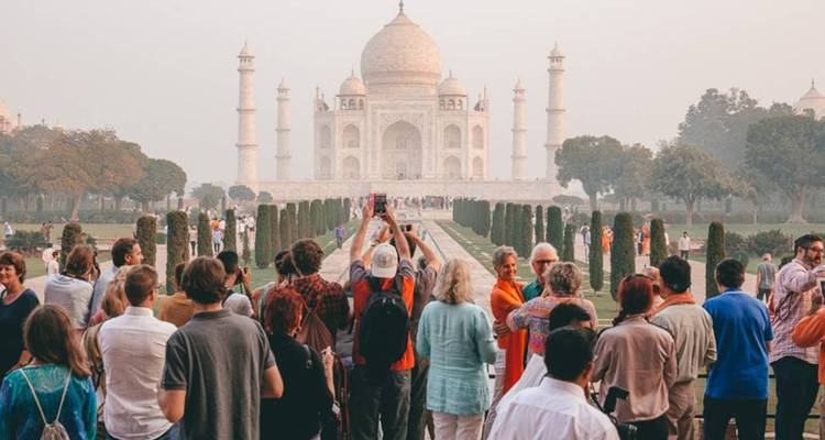 Menigten bezoekers die poseren op het centrale pad dat naar de Taj Mahal leidt bij dageraad.