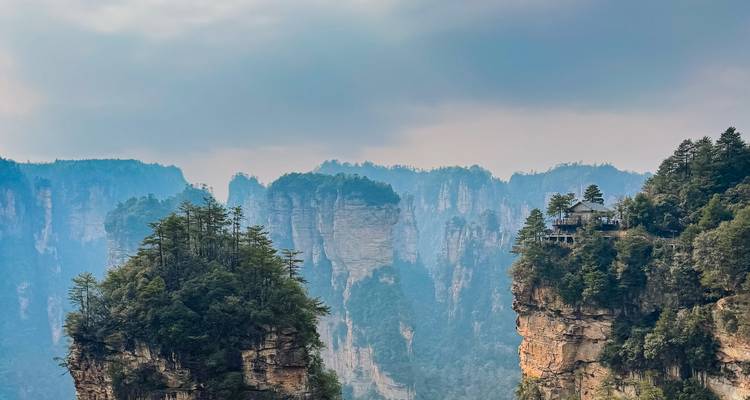 Mist-filled view of sheer sandstone pillars and forested cliffs in Zhangjiajie National Park.