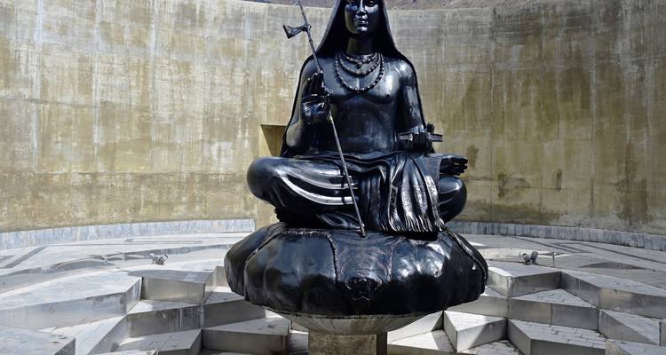 Statue noire polie d'Adi Shankaracharya assis en méditation dans un sanctuaire circulaire en béton.