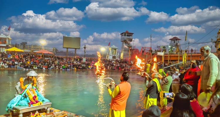 Cérémonie d'Aarti du Ganga en soirée à Haridwar avec des prêtres tenant des torches enflammées devant une grande foule au bord de la rivière.