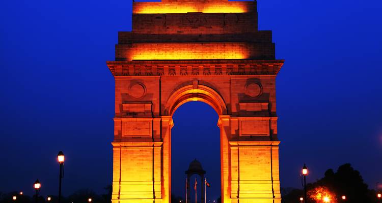 Le mémorial de guerre India Gate à Delhi brillant d'un éclat doré contre un ciel nocturne d'un bleu profond.