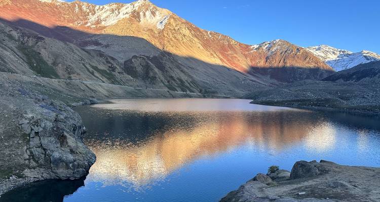 Pristine alpine lake mirroring rugged peaks under a clear blue sky