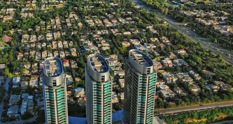 Aerial view of three modern high-rise towers overlooking a grid of city houses