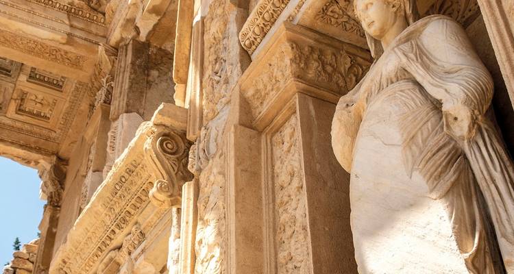 Gros plan de la façade ornée d'une ancienne bibliothèque en pierre avec statue féminine et sculptures complexes