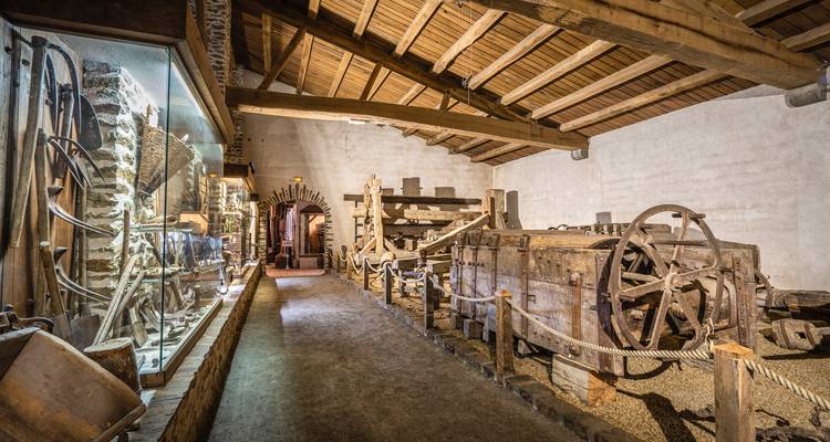Breiter Korridor in historischem Museum mit hölzernen Industriemaschinen und Werkzeugen unter Holzdach.