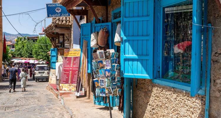 Rue charmante bordée de volets bleu vif et d'étals de souvenirs dans une ville perchée.