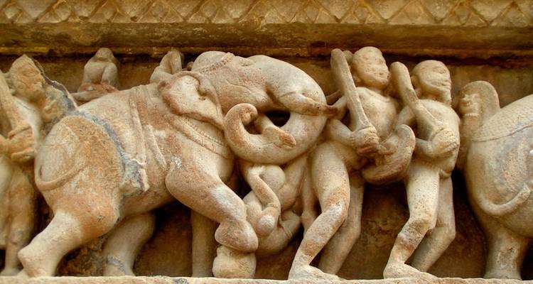 Gedetailleerde steenbewerking van olifanten en krijgers op een Khajuraho tempelfries