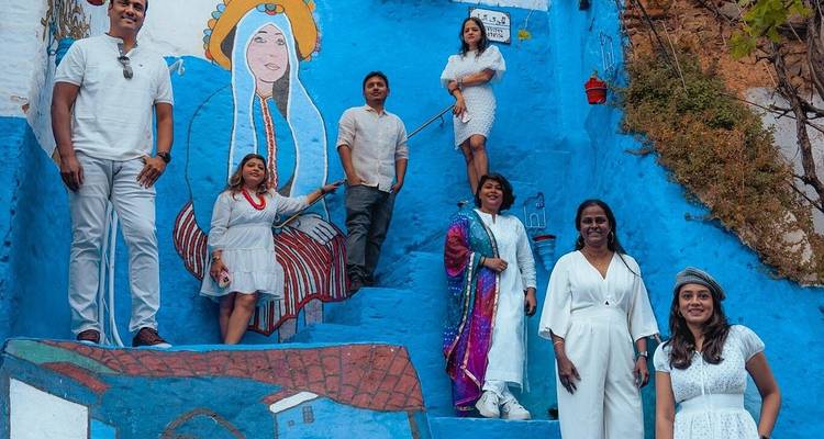 Groep reizigers poseert op helderblauwe trap met Marokkaanse muurschildering in de medina van Chefchaouen
