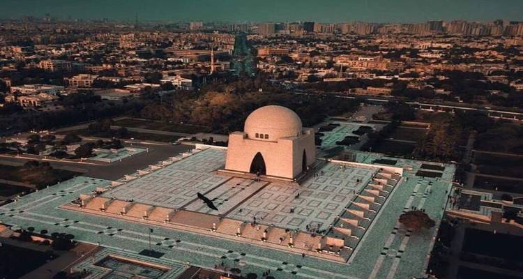 Vista aérea al amanecer del mausoleo Mazar-e-Quaid rodeado de jardines geométricos y el horizonte de Karachi