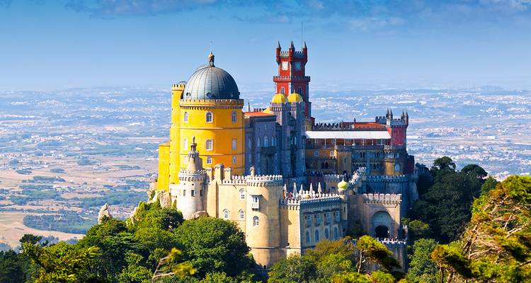Colorido Palacio da Pena como de cuento de hadas encaramado en la cima de una colina boscosa con vista a las llanuras de Portugal
