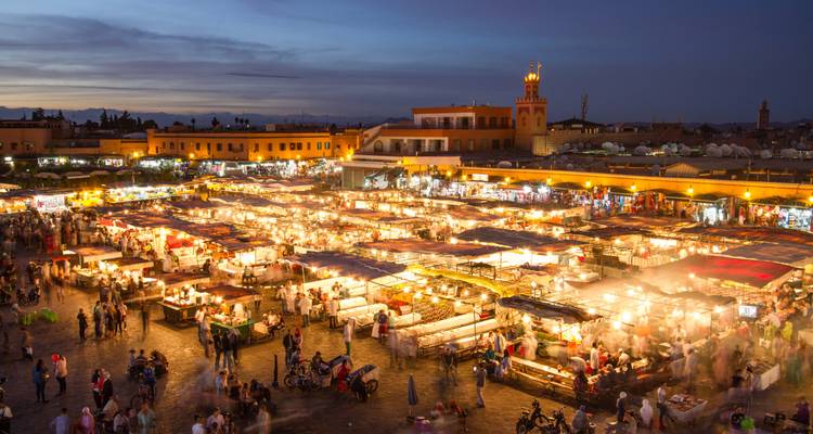 Nighttime aerial view of bustling Jemaa el-Fna square filled with illuminated food stalls and crowds in Marrakesh
