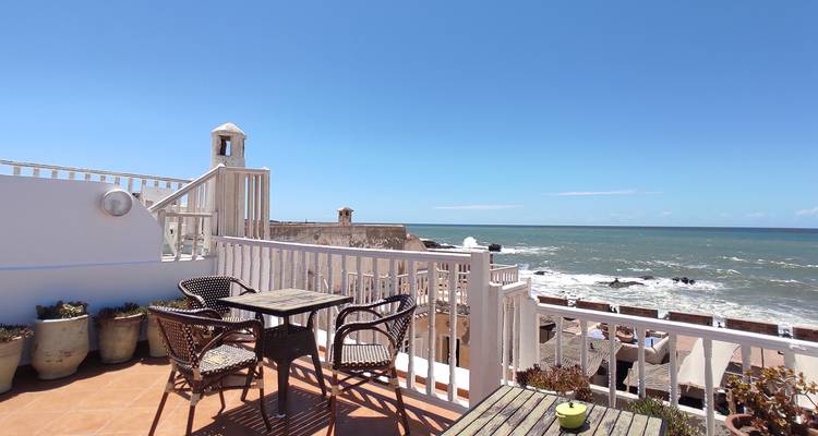 Sunny rooftop terrace with table and chairs overlooking the Atlantic Ocean in Essaouira