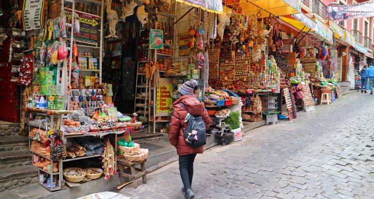 Voyageur en manteau d'hiver parcourt les étals colorés le long d'une rue pavée du Marché aux Sorcières de La Paz.