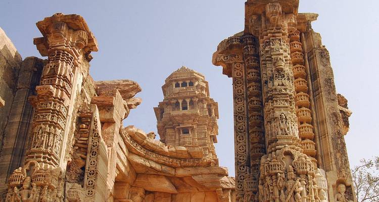 Des piliers en grès finement sculptés et une tour de guet s'élèvent contre un ciel dégagé à l'intérieur du fort de Chittorgarh.