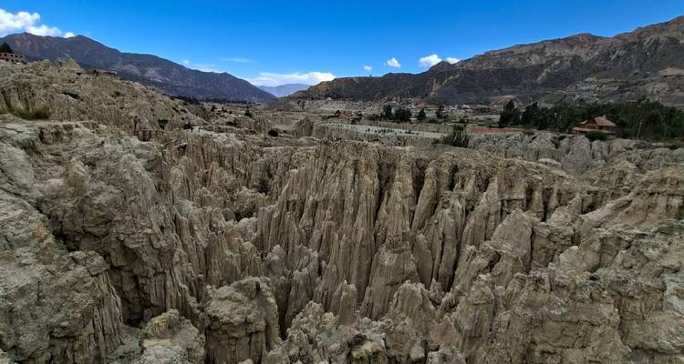 Geërodeerde kleipieken en ravijnen van Bolivia's Vallei van de Maan met bergen en lucht in de verte.