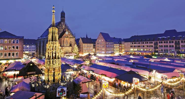 Des stands de marché de Noël illuminés entourent la fontaine ornée Schöner Brunnen à Nuremberg au crépuscule.