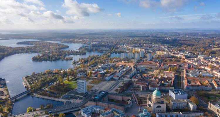Panorama aérien de Potsdam avec le dôme de l'église baroque, les voies navigables et la mosaïque de rues historiques.