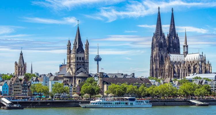 Cologne’s Gothic cathedral and historic skyline rise above the Rhine on a bright day.