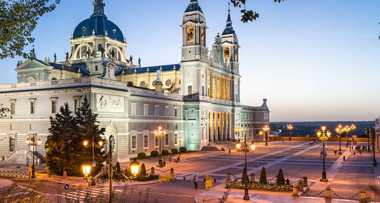 Elegant evening view of Madrid’s Almudena Cathedral and surrounding square softly lit at dusk.