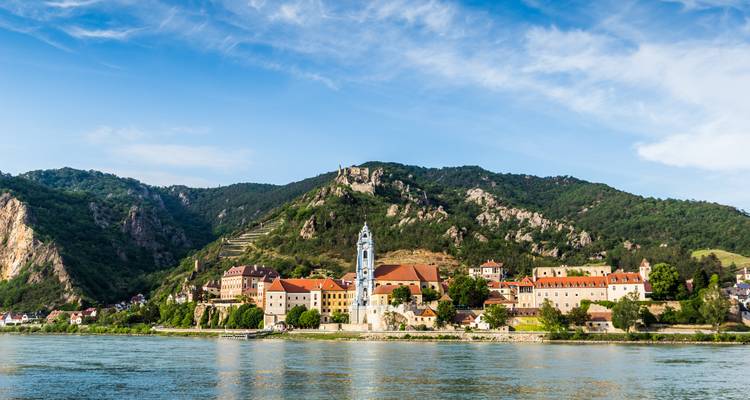 Charming Danube riverside town of Dürnstein with blue church tower set against wooded hills.