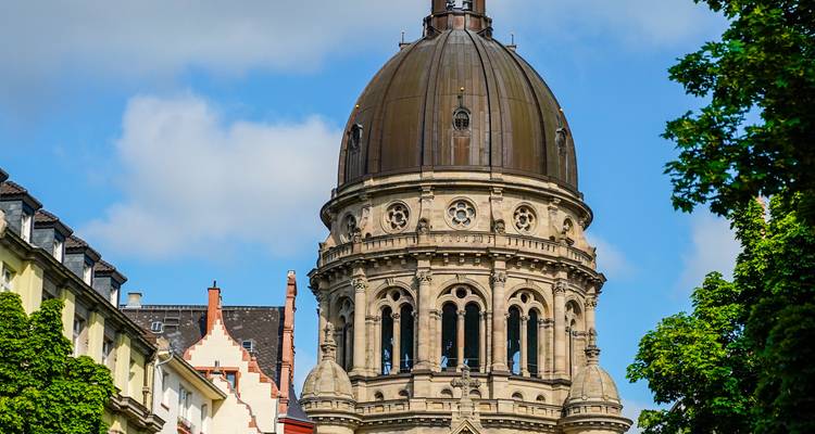 Historic stone dome rising above colourful town buildings under a bright sky.