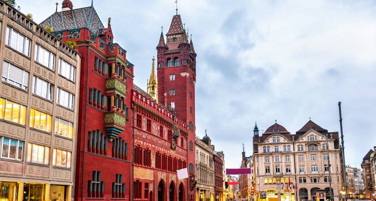 Bâtiment historique de l'hôtel de ville rouge avec façade ornée sous un ciel nuageux.