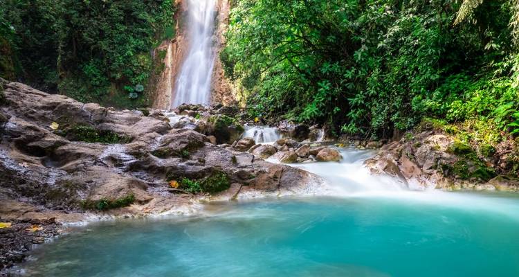 Cascada sedosa cae en una piscina turquesa rodeada de exuberante selva tropical.