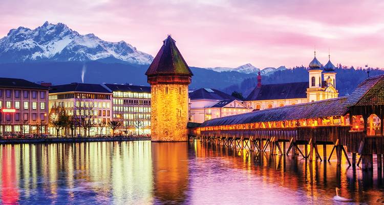 Evening glow over Lucerne’s Chapel Bridge reflected in the Reuss with snow-capped Mount Pilatus in the background.