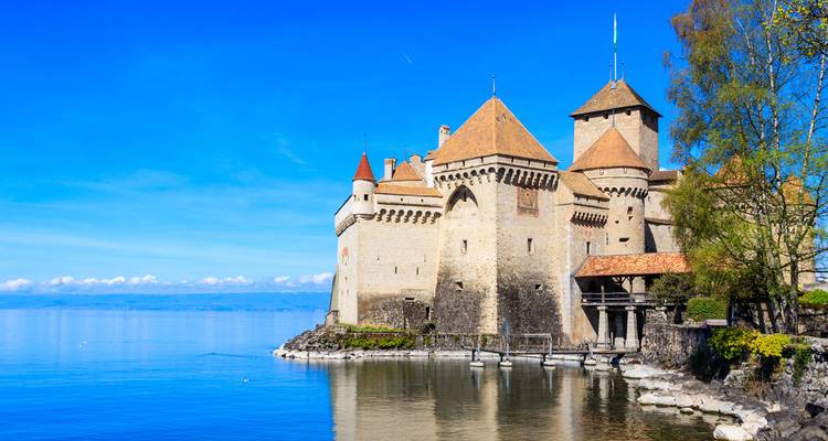 Château médiéval de Chillon sur les eaux bleues tranquilles du lac Léman sous un ciel dégagé.
