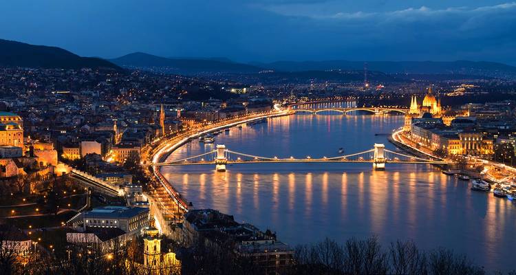 Night view of Budapest city lights stretching along the Danube with bridges and parliament glowing.