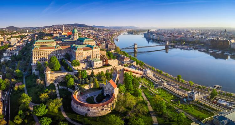 Panoramic aerial of Budapest’s Buda Castle and Chain Bridge spanning the Danube on a clear morning.